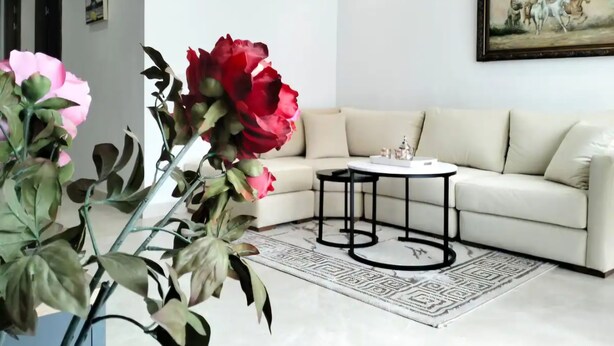 Un salón moderno con un sofá beige, una mesa de centro redonda y un cuadro grande en la pared.