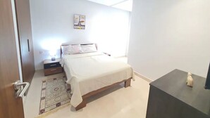 Un dormitorio con cama, mesita de noche y una pequeña mesa con un adorno.