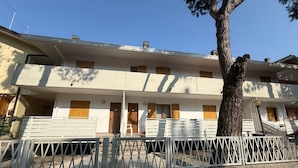Un bâtiment à deux étages, doté d’une façade blanche, de nombreuses fenêtres et d’un arbre devant.
