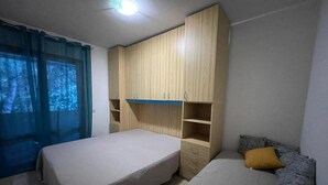 Une chambre avec deux lits, une armoire en bois et une fenêtre avec des rideaux.