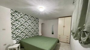 Ein Schlafzimmer mit einem Bett, einem Nachttisch, einem Kleiderschrank und einer Wand mit Muster.