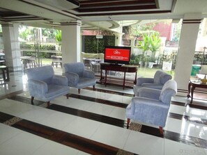 A lobby with a TV, seating area, and a view of the outdoors. - Hotel Centro Puerto Princesa Near Airport by Zuzu (Puerto Princesa)