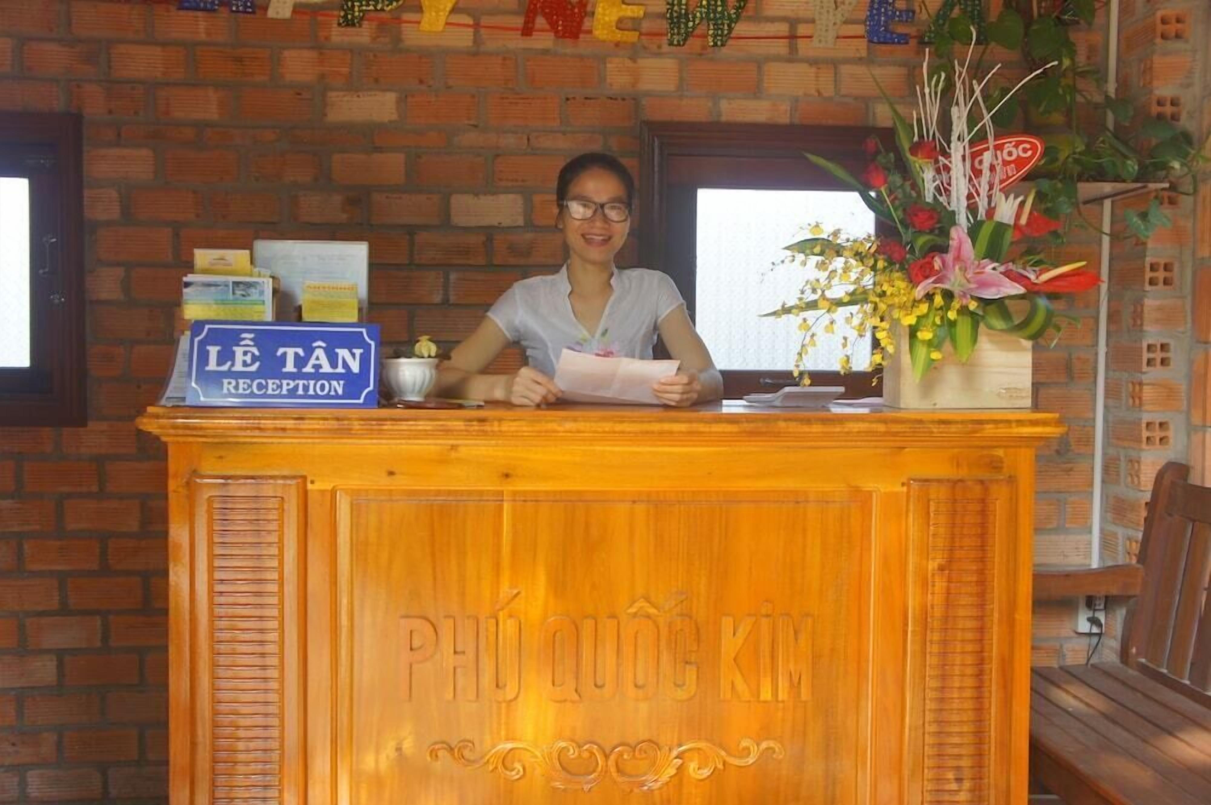 Un comptoir d’accueil avec une enseigne indiquant « RÉCEPTION LE TAN » et les mots « PHU QUOC KIM » gravés dessus.