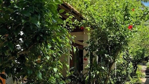 Ein Gartenpfad führt zu einem Gebäude mit einer Backsteinarchitektur, umgeben von üppigem Grün und roten Blumen.