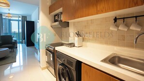 A modern kitchen with wooden cabinets, a built-in dishwasher, and a stainless steel sink. - Bloomfields Spectacular STU Julphar (Abu Dhabi)