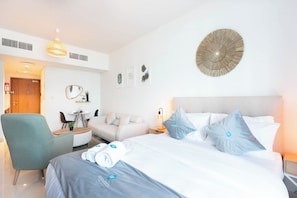 A modern hotel room with a bed, a desk, a chair, and a round wall decoration. - Bloomfields Studio in Julphar-Al Reem (Abu Dhabi)