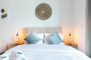 A neatly made bed with two pillows, a decorative wall piece, and two bedside lamps.