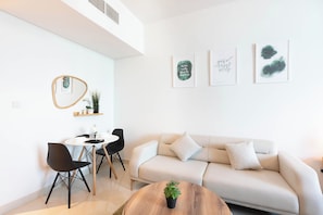 A modern living room with a sofa, a coffee table, and a dining area with chairs and a table.