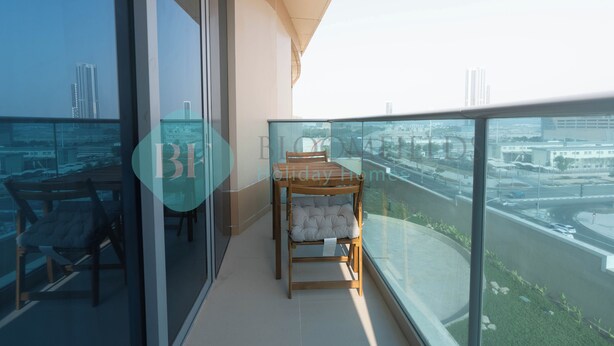 A balcony with a glass railing, a wooden table, and two chairs. - Bloomfields Spectacular STU Julphar (Abu Dhabi)