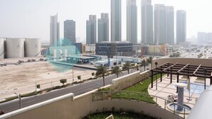 A cityscape with high-rise buildings, a parking area, and a landscaped area with a fountain. - Bloomfields Spectacular STU Julphar (Abu Dhabi)