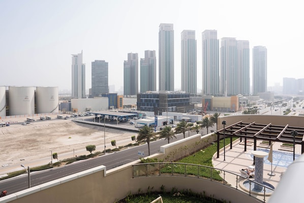 A high-rise building complex with modern architecture, a parking area, and a landscaped area with a pool.