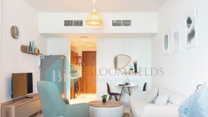 A modern hotel room with a bed, a sofa, a TV, a dining table, and a chair. - Bloomfields Spectacular STU Julphar (Abu Dhabi)