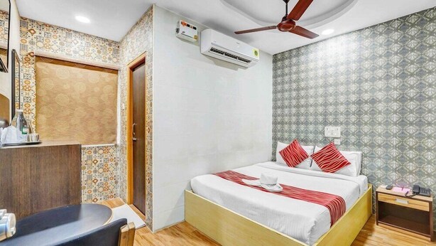 Habitació d'hotel amb llit, escriptori, aire condicionat, ventilador de sostre i paper de paret amb disseny.