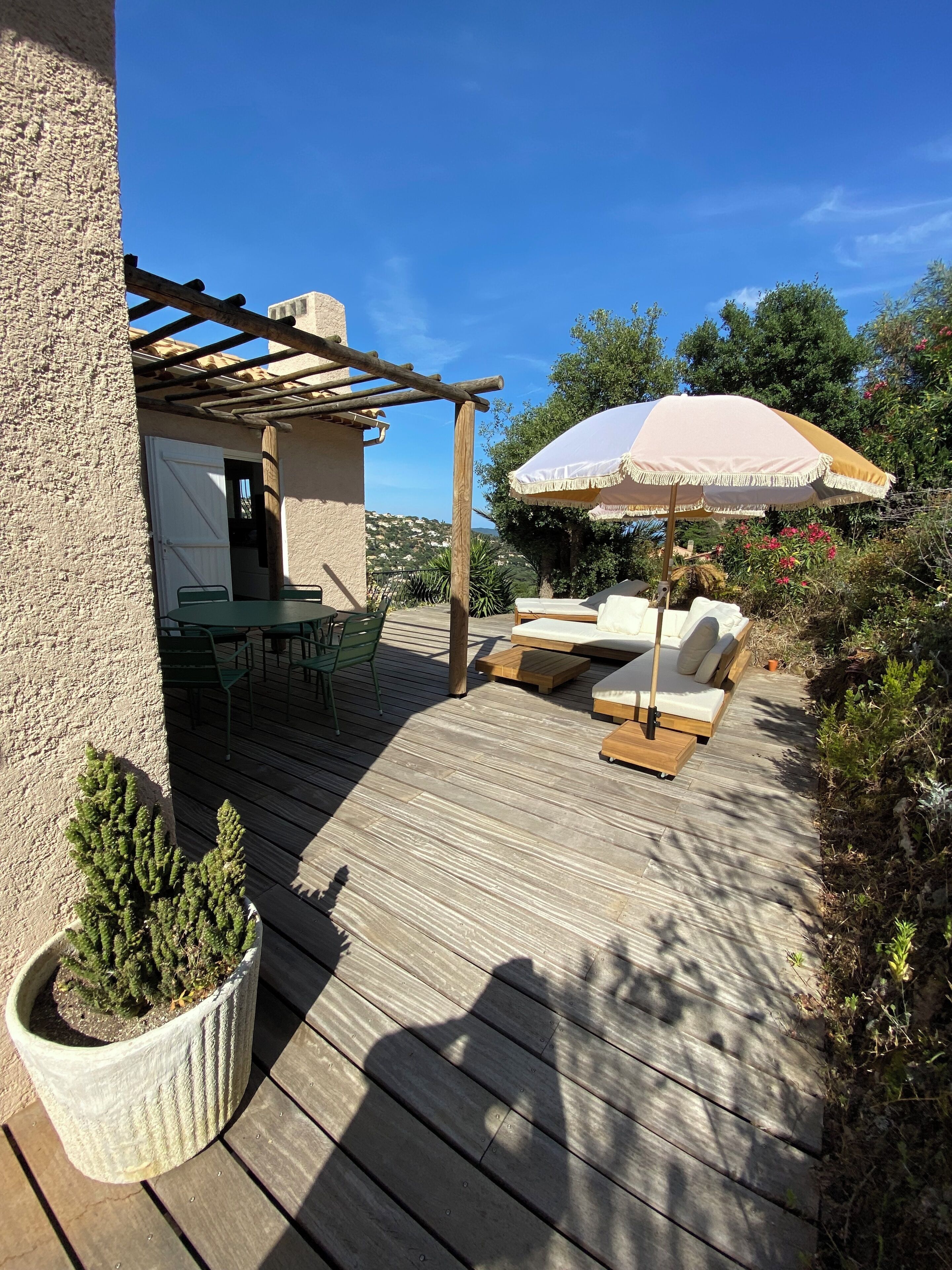 A wooden deck with outdoor furniture, a pergola, and a potted plant.