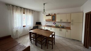 A compact kitchen with a dining table, chairs, a TV, and cabinets. - Solaris, trilocale: 72  (Rosolina Mare RO)