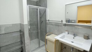 A modern bathroom with a glass-enclosed shower, a white sink with a mirror above, and a towel rack. - Cozy Apartment in Rosolina for 4 (Rosolina Mare RO)