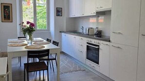 Una cocina moderna con armarios blancos, horno integrado y una zona de comedor con mesa y sillas.
