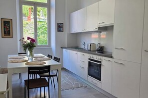Eine moderne Küche mit weißen Schränken, einem eingebauten Backofen und einem Essbereich mit Tisch und Stühlen.