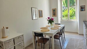 Un comedor con una mesa blanca dispuesta para cuatro personas, rodeado de cestas de mimbre y sillas.