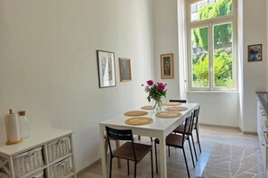 Ein Essbereich mit einem weißen Tisch, gedeckt für vier Personen, umgeben von Korbmöbeln und Stühlen.