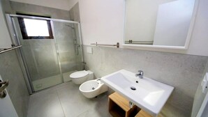 Ein Badezimmer mit Duschkabine, Toilette und Waschbecken.