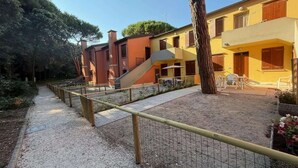 Une cour avec un chemin de gravier, une clôture en bois et des bâtiments dotés de balcons et de fenêtres.