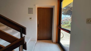 Un corridoio con una porta in legno, una scala e una finestra che dà su un panorama esterno.