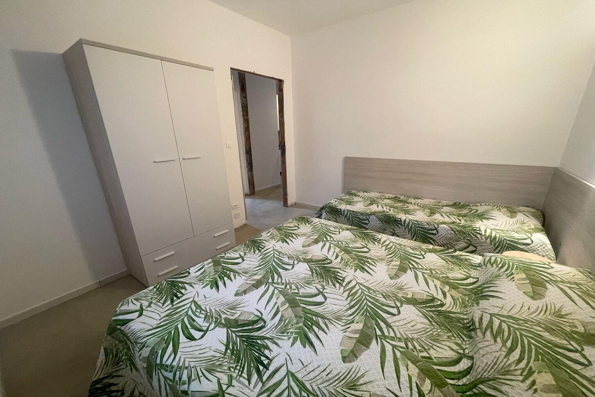 Una camera da letto con due letti, un armadio e una porta che dà su un'altra stanza.