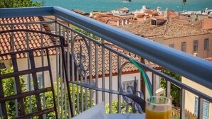 A balcony with a view of a body of water, a distant island, and buildings in the background. - Acronafplia Pension B&D (Nafplio)