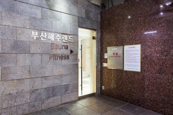 Entrada de un edificio con un letrero que indica sauna y gimnasio.