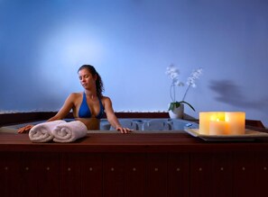 A person in a bathtub with towels and a lit candle on the side. - Katrin Suites (Hersonissos)