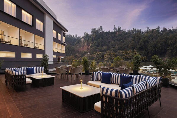 Terraza en la azotea con mobiliario exterior, piscina y vistas a una ladera boscosa.