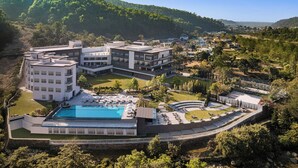 Ein modernes Hotel mit mehreren Gebäuden, einem Schwimmbad und angelegten Gärten.