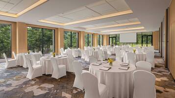 A conference room with round tables, white chairs, and a large screen.