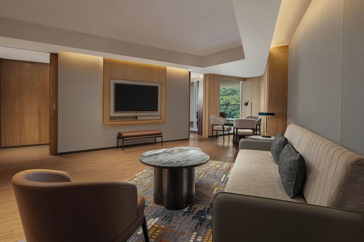 A modern living room with a large flat-screen TV, comfortable seating, and a wooden floor.