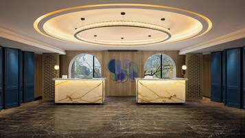 A reception area with two marble reception desks, a circular ceiling light fixture, and a large abstract wall art piece.