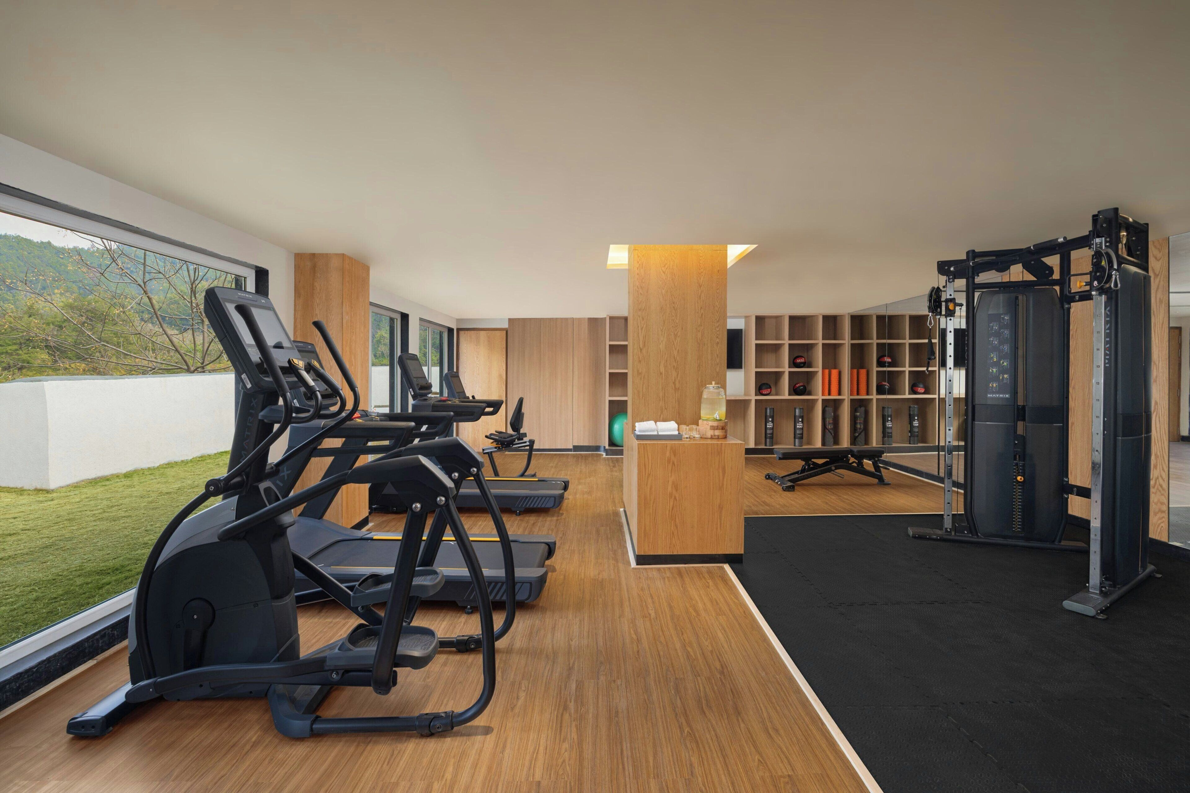 Un gimnasio moderno con cintas de correr, máquinas de pesas y una recepción.
