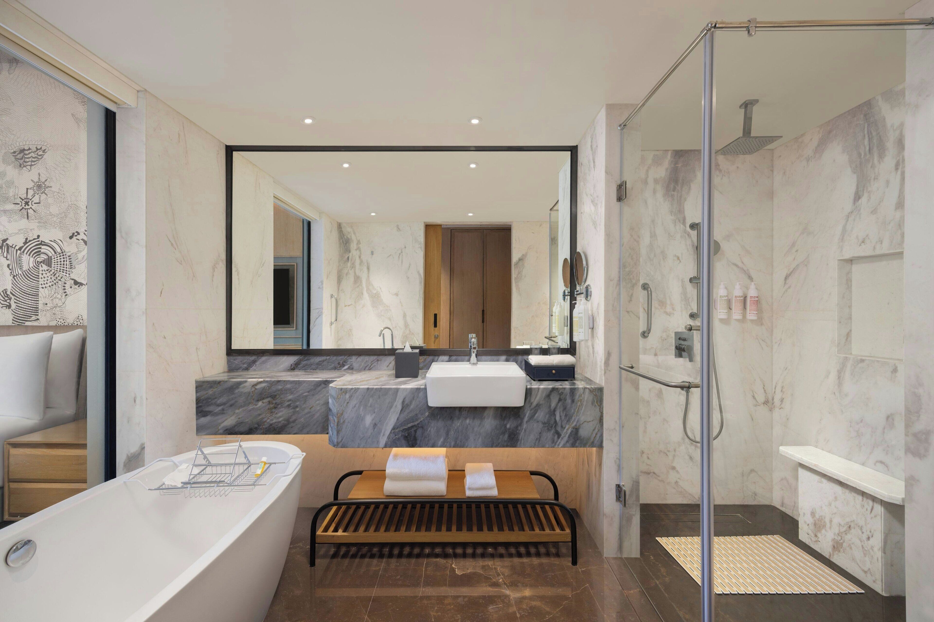 A modern bathroom with a bathtub, a shower, a vanity with a sink, and a large mirror.