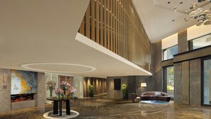 Eine großzügige Lobby mit hoher Decke, einer zentralen Sitzecke und einem Kamin.
