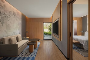 A modern hotel room with a sofa, a TV, a bed, and a small table. - Le Méridien Dehradun India Resort & Spa (DEHRADUN)