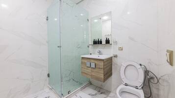 A modern bathroom with a glass shower enclosure, a wooden vanity, a white sink, and a toilet.
