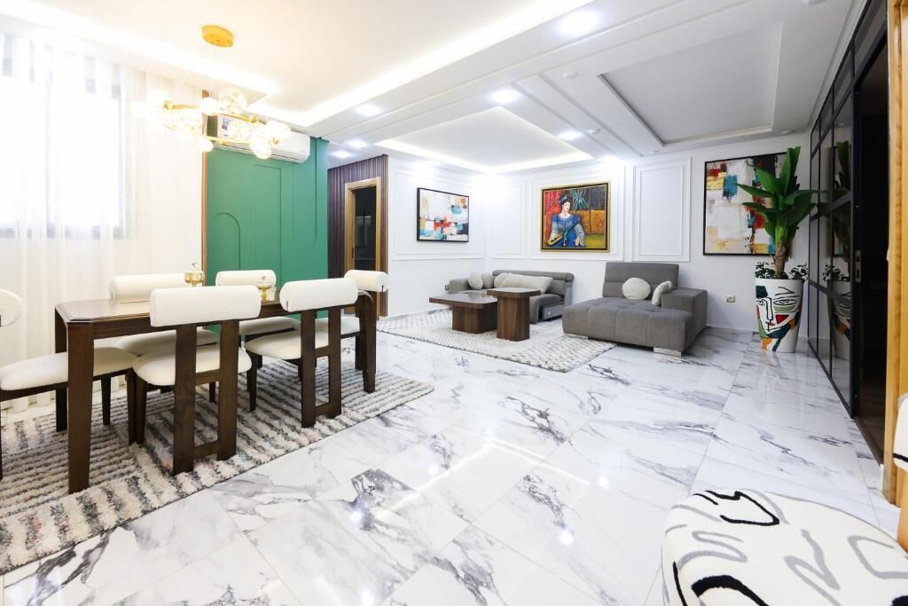 A modern living room with a dining area, marble flooring, and contemporary furniture.