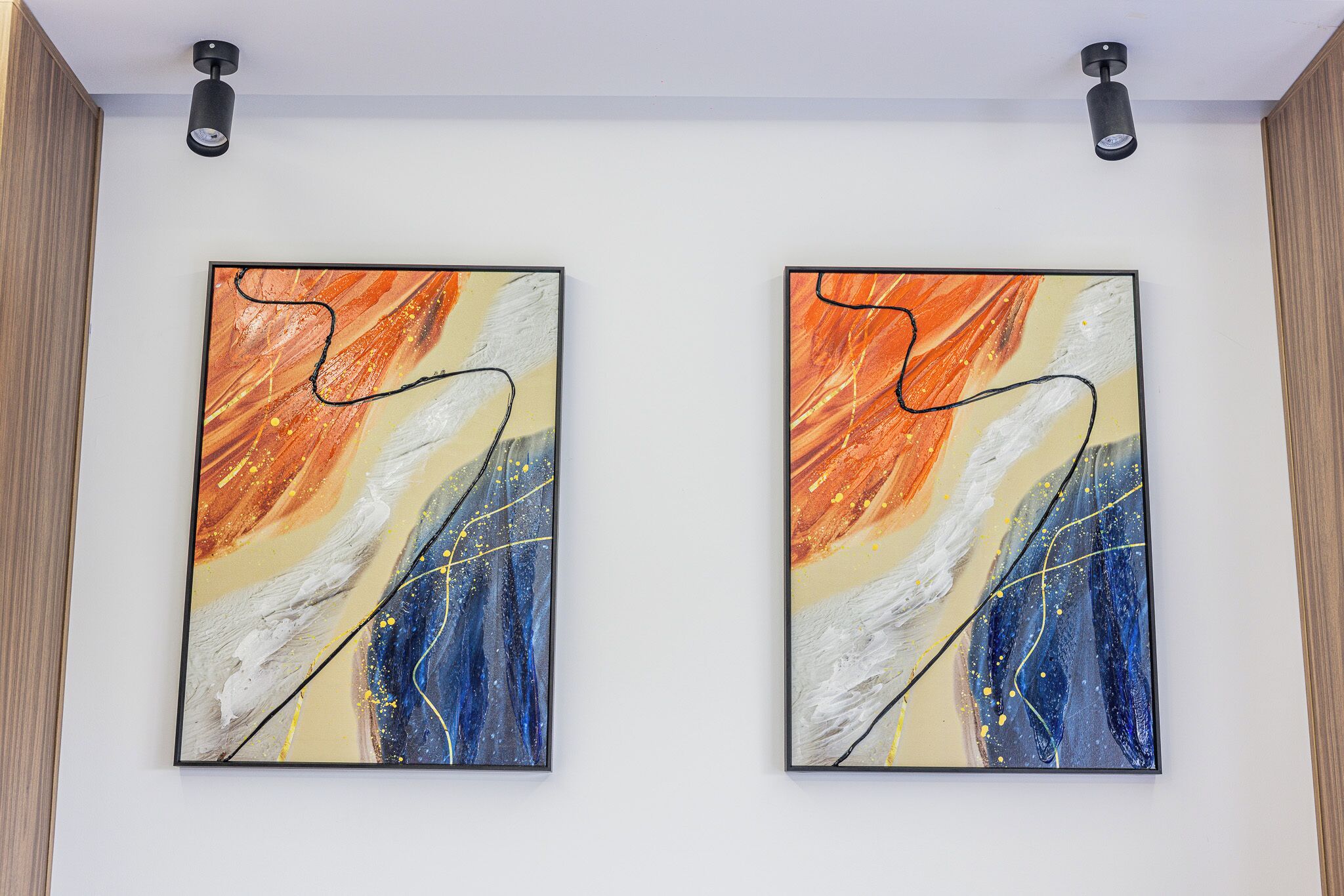 Two abstract paintings on a white wall.