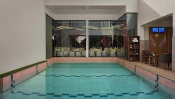 A swimming pool with a view of the sky, a reception area with a sign reading 'Bay Side', and a seating area with chairs and a table.