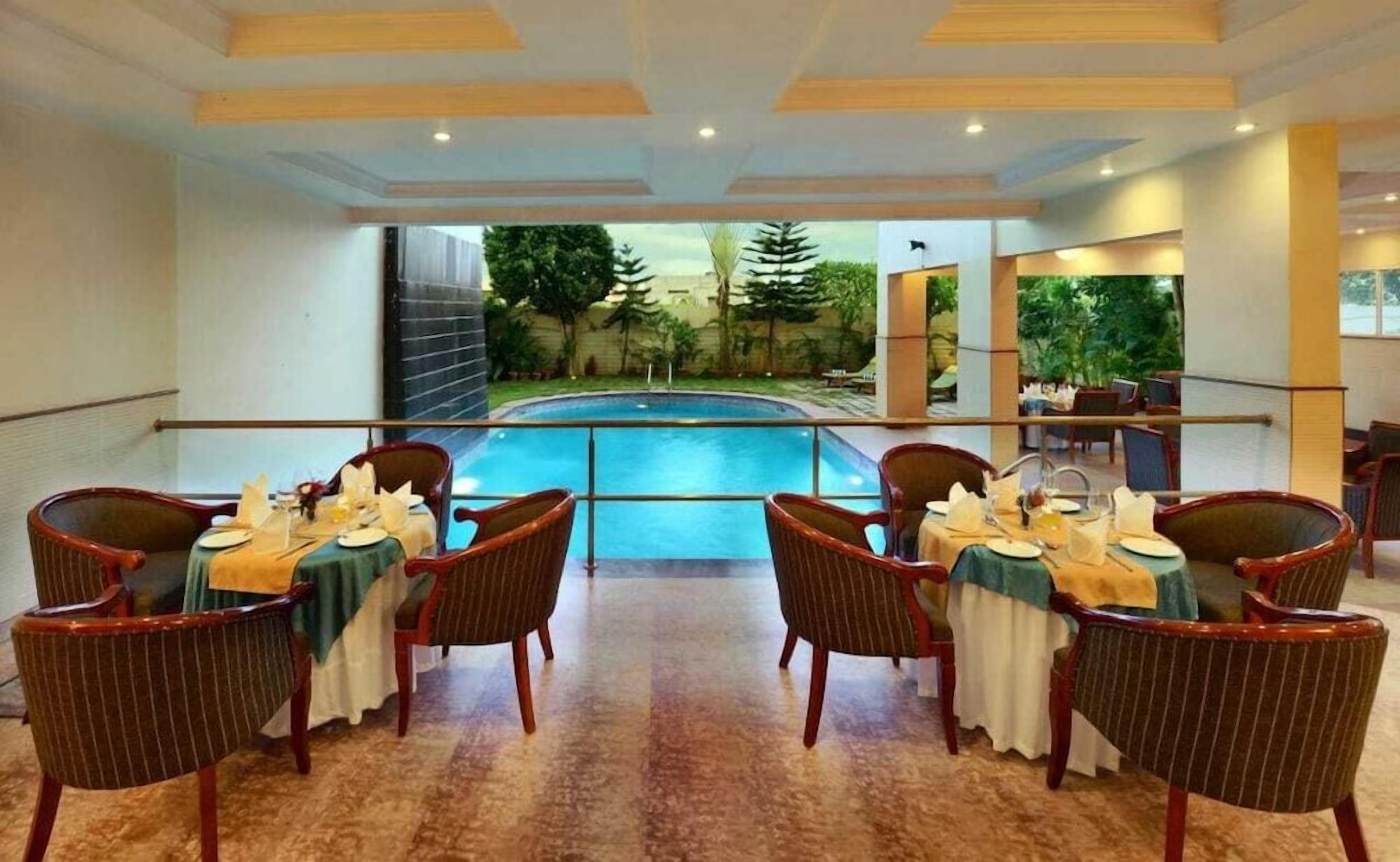 Un comedor con mesas dispuestas para cuatro, con vista a una piscina.