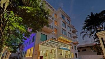 A multi-story hotel with a glass entrance, balconies, and a covered outdoor area.