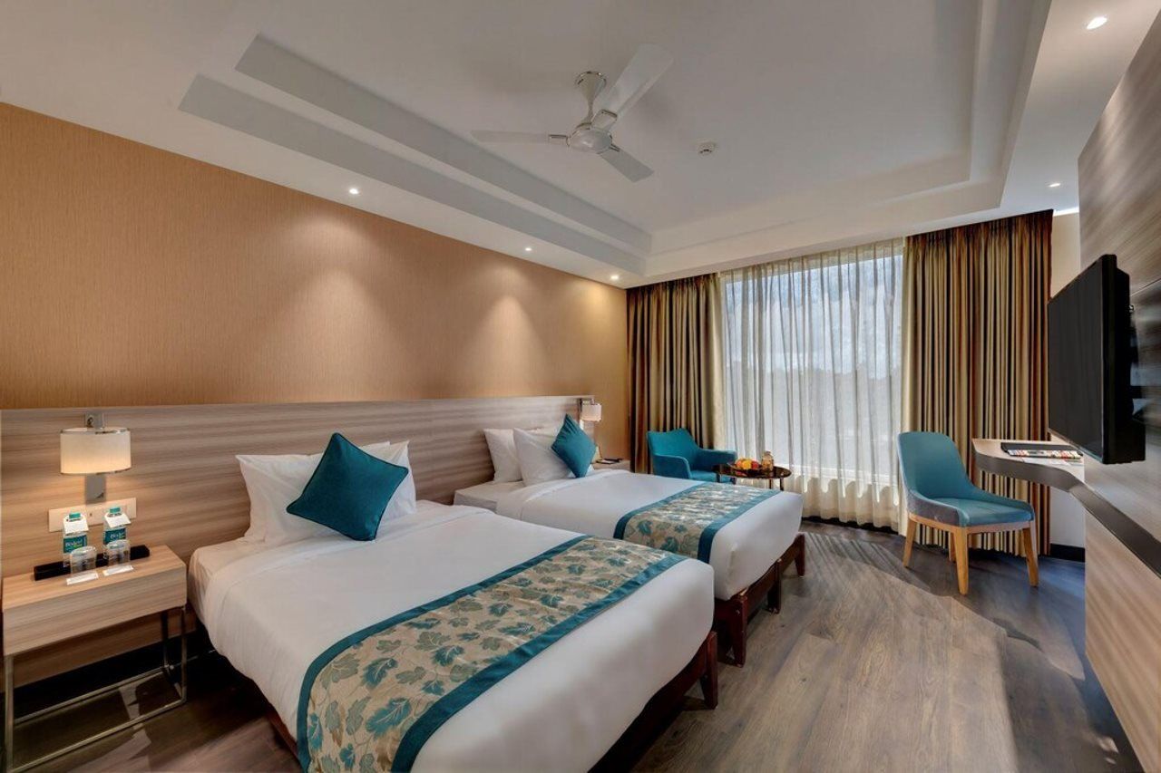 A hotel room with two beds, a TV, a desk, and a chair.