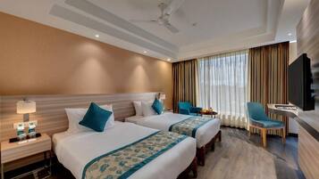 A hotel room with two beds, a TV, a desk, and a chair.