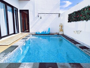 A swimming pool with a tiled floor, a wooden deck, and a wall-mounted heater. - Joy Private Pool House (Kuta)