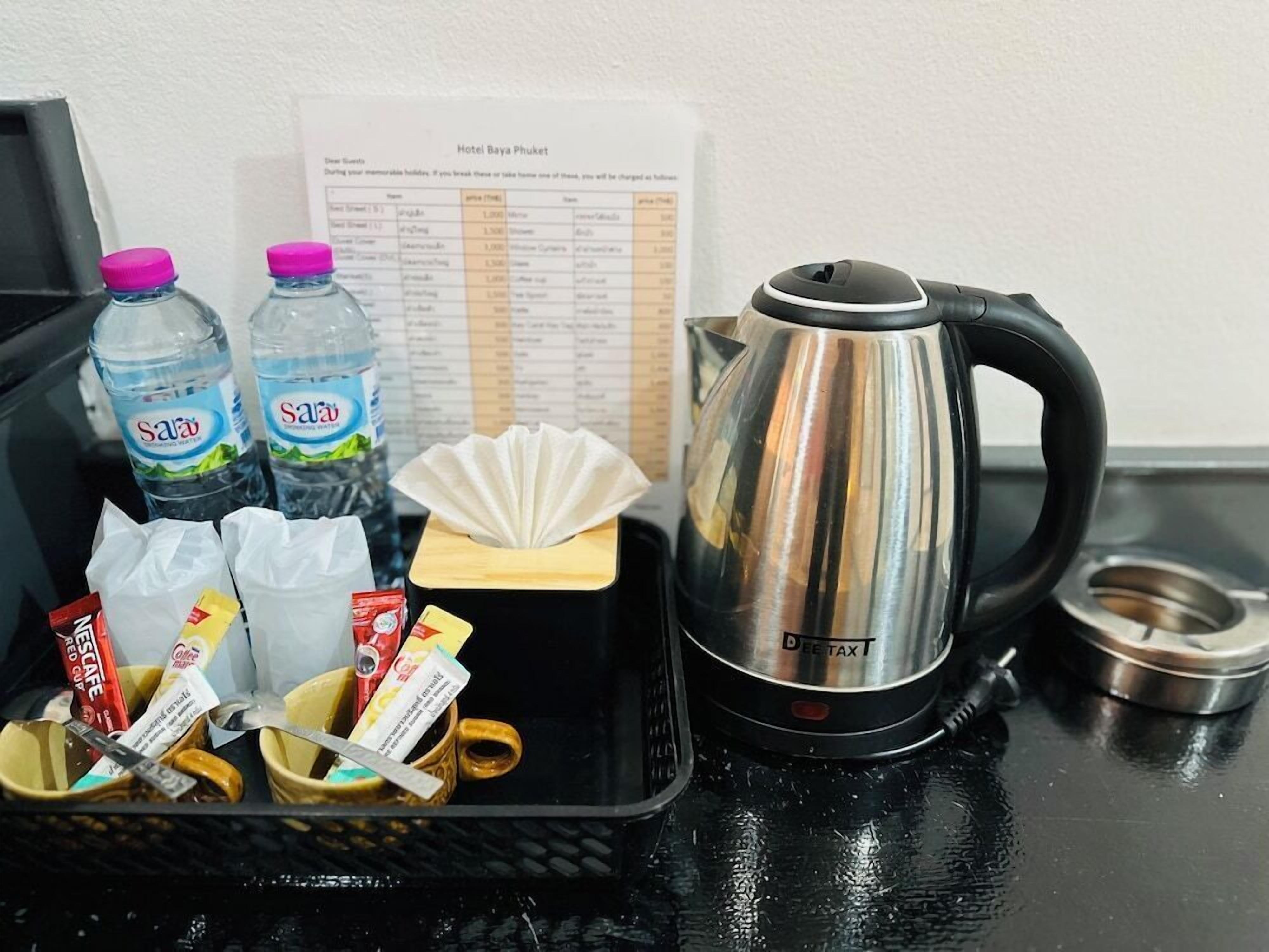 A minibar setup with a kettle, water bottles, snacks, and a menu.
